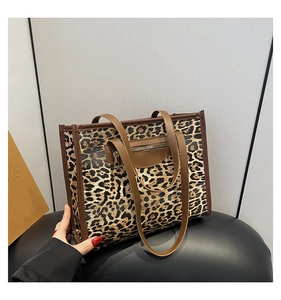 Detail of leopard print tote bag featuring a brown faux leather trim and front zipper pocket