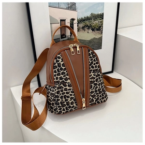 Detail of mini leopard print backpack featuring dual gold zippers and brown leather trim