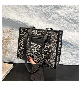 Detail of leopard print tote bag featuring black shoulder strap and gold zipper pocket