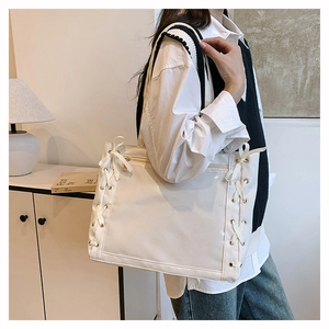 Dettaglio della borsa tote bianca con fiocchi laterali a coulisse e occhielli in metallo