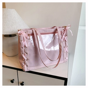 Close-up of pink ita bag featuring a transparent PVC window and side ribbon lace-up detail