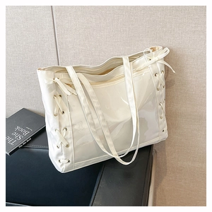 Dettaglio di borsa tote bianca lucida con lacci in nastro e fiocchi decorativi laterali