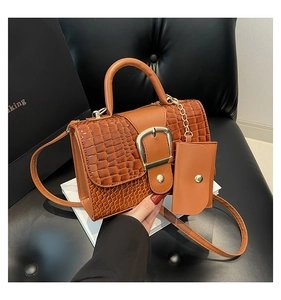 Détail du sac en cuir crocodile orange-brun avec boucle dorée et mini pochette suspendue