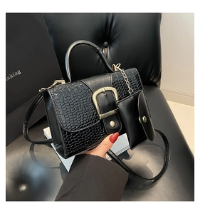 Détail d'un sac en similicuir noir avec texture crocodile et boucle dorée