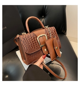 Vue détaillée de la texture crocodile marron foncé et de la boucle en métal doré du sac