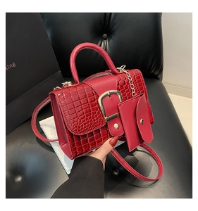 Vue à la main d'un sac rouge motif crocodile avec boucle dorée et détail de chaîne