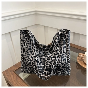 Detail view of large leopard print tote bag with metal magnetic closure on a table