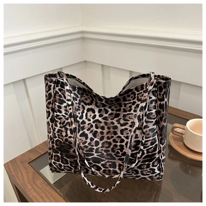 Close-up of leopard print tote bag placed on a rustic wooden table next to a coffee cup