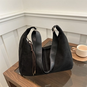 Borsa tote nera minimalista con ampia tracolla in nylon su un tavolo di legno in un interno