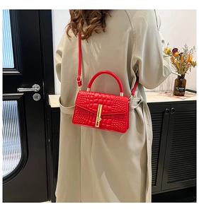 Macro shot of red crocodile texture handbag with elegant gold metal lock and leather strap