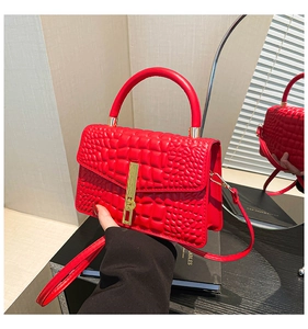 Macro shot of red faux crocodile leather texture and gold buckle on a stylish handbag