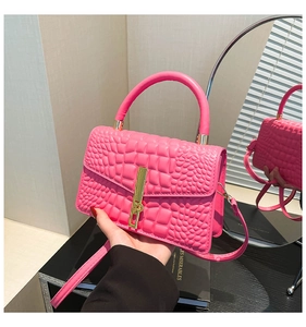 Detail of pink croc-effect handbag with gold lock and adjustable shoulder strap