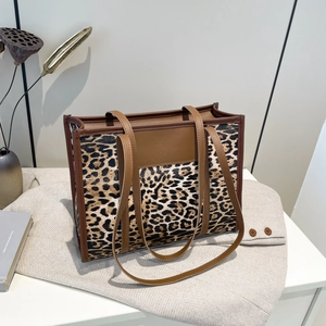 Large leopard print tote bag with brown leather handles in a stylish minimalist setting