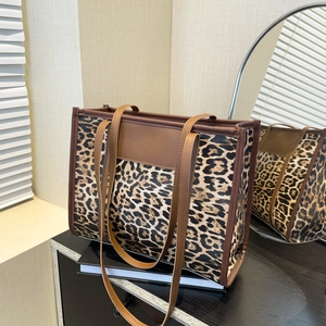 Large leopard print tote bag with dark brown trim on a modern cabinet surface