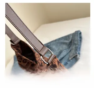 Detail of leopard print tote bag with brown leather strap and silver metal buckle attachment