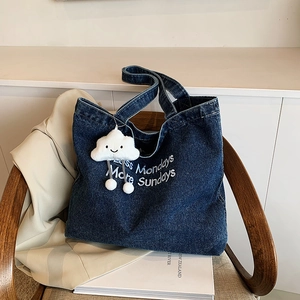 Retro denim tote bag with embroidery lettering and cloud charm on a wooden chair