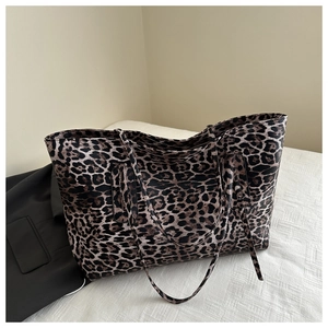 Detail view of large leopard print tote bag with long straps beside a black blazer