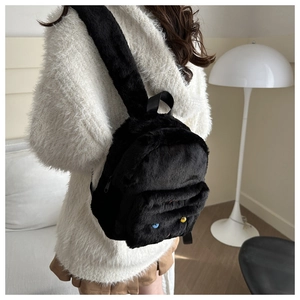 Détail du sac à dos en peluche noire avec boutons colorés et texture douce