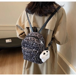 Detail of leopard print mini backpack on model showing size and funny plush charm accessory
