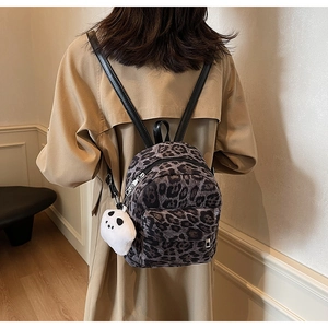 Close-up of leopard print mini backpack with panda plush charm shown on a model