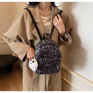 Close-up of leopard print mini backpack with cute ghost charm on a khaki trench coat