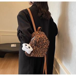 Detail view of leopard print mini backpack with cute panda charm and brown leather straps