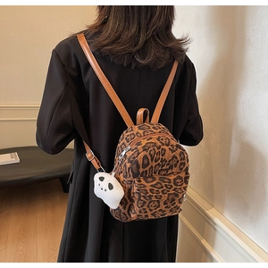 Leopard print mini backpack with brown leather straps and a panda plush charm