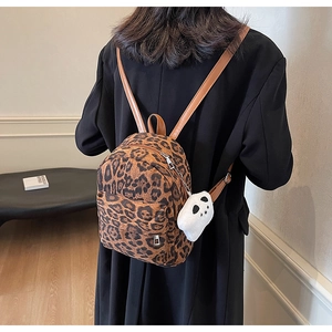 Detail of leopard print backpack with brown leather straps and cute white ghost charm