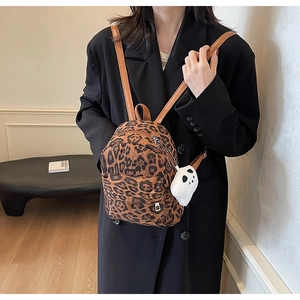 Close-up of leopard print mini backpack featuring a plush ghost charm and leather straps