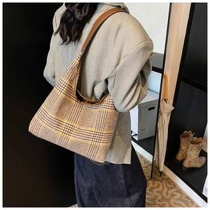 Detail view of large-capacity houndstooth shoulder bag for women on a stylish model