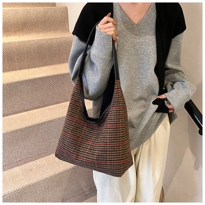 Lifestyle shot of large plaid hobo shoulder bag styled with a grey sweater and white pants