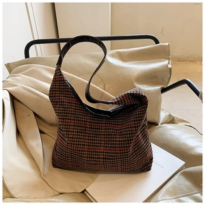 Detail of houndstooth plaid pattern on vintage shoulder bag with black leather strap