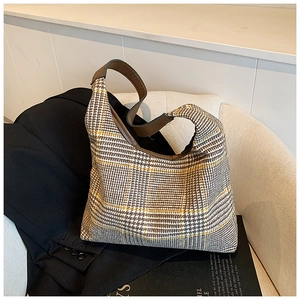 Detail of retro houndstooth tote bag texture with brown leather handle on a chair