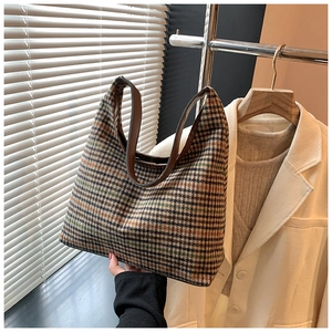 Detail view of retro plaid canvas tote bag with brown leather handles on white blazer