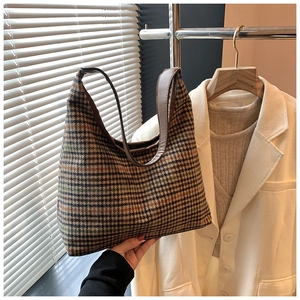 Close-up of retro plaid hobo bag with brown leather strap and wool texture details
