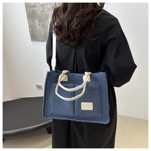 Detailed view of deep blue canvas tote bag with functional front pockets on female model