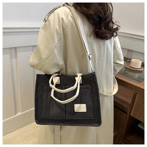 Detail of dark grey canvas tote bag featuring adjustable straps and JINGPIN woven label