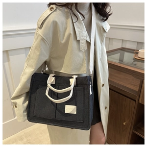 Detail of grey canvas tote bag with front pockets and adjustable white shoulder strap