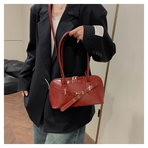Close-up of retro dark red shiny shell bag with metal buckle and fashion logo text