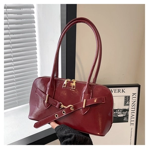 Detail of burgundy glossy shell bag featuring metallic strap and double zip closure
