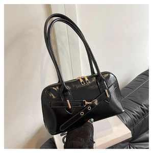 Detail of a black glossy shell bag featuring gold zippers and embossed fashion logo