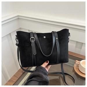 Detail of black faux suede tote bag featuring metallic rivets and leather handles