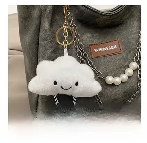 Close-up of a plush white smiling cloud charm with striped legs on a grey denim bag