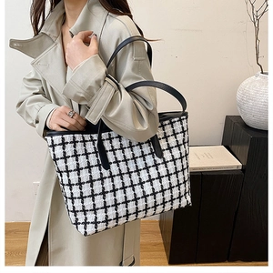 Detail of checkered tote bag on beige coat with textured fabric and leather straps