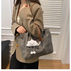 Detail of grey tote bag with leather handles, cloud charm, and pearl chain decoration