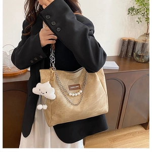 Detail of beige tote bag featuring a metallic pearl chain and plush cloud charm