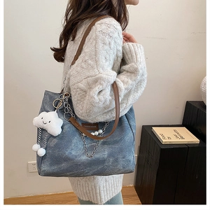 Detail of blue denim tote bag with brown leather straps and pearl chain accessory