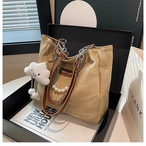 Detail of khaki canvas tote bag with pearl chain, leather strap and cloud charm
