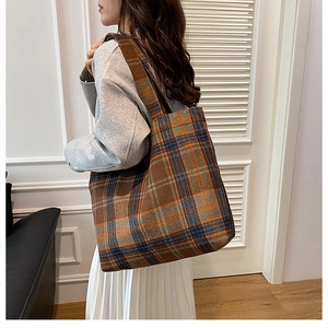 Detail view of retro plaid tote bag made of thick wool fabric on a female model
