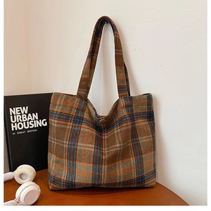 Close-up of brown plaid tote bag texture with button closure and long shoulder strap